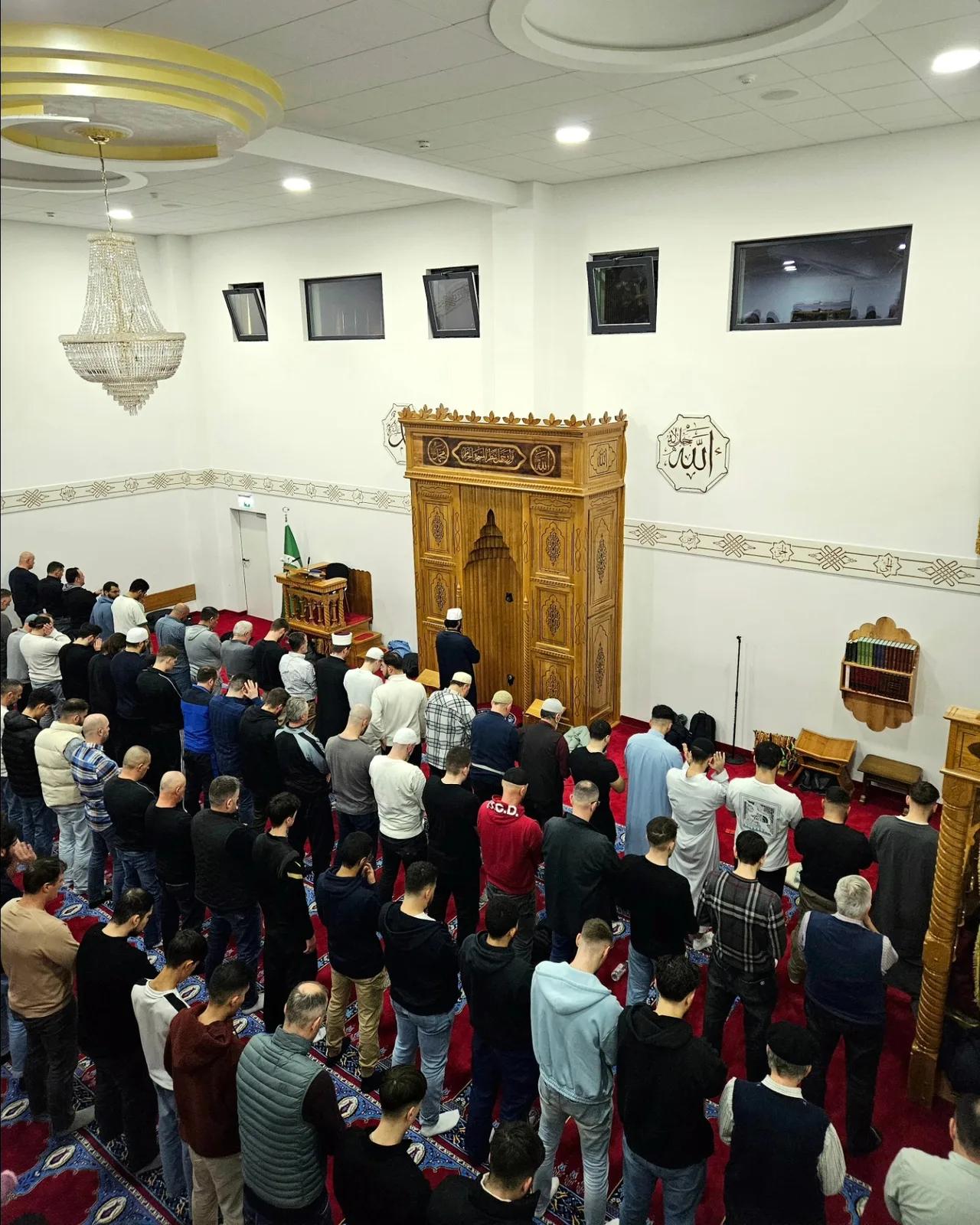 Weite Reihen Betender in einem großen Saal mit Kronleuchtern