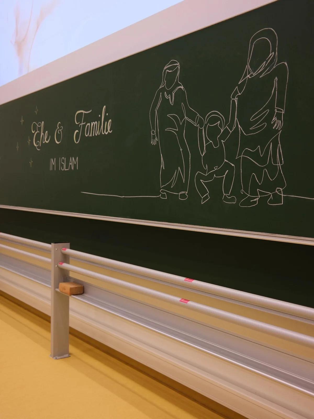 Referent sitzt im Kerzenlicht vor der Tafel zu Imam al-Ghazali