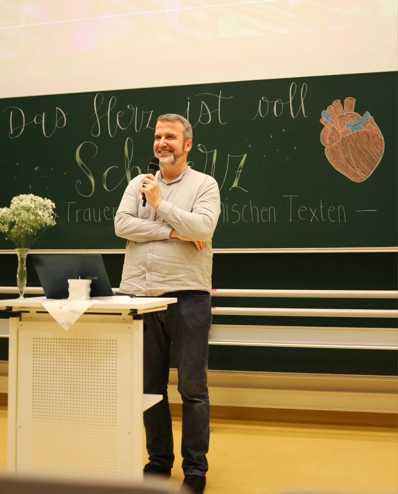 Referent steht vor der Tafel Das Herz ist voll Schmerz