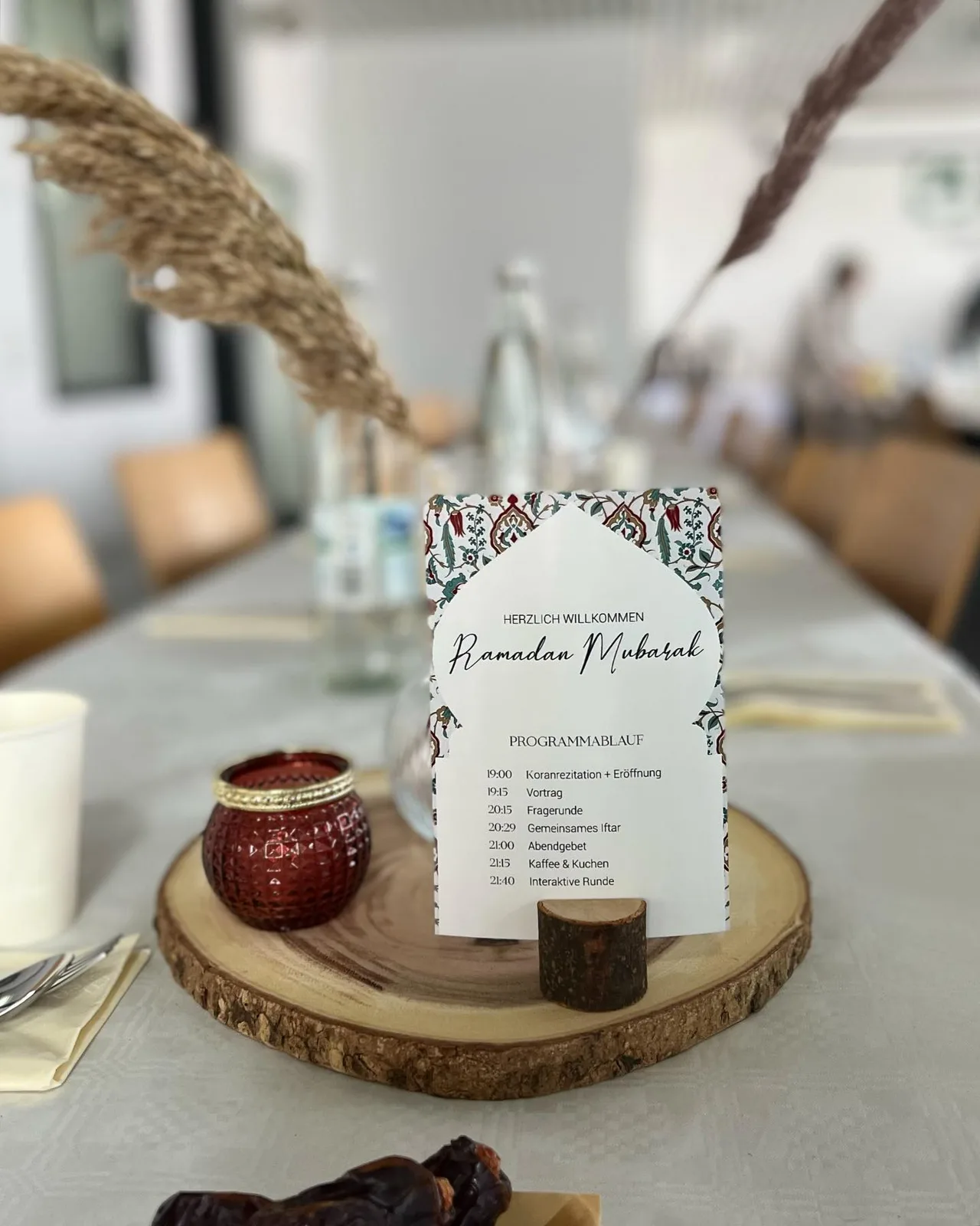 Eine Tischdekoration zum Ramadan mit Karte, Kerze und Trockengräsern