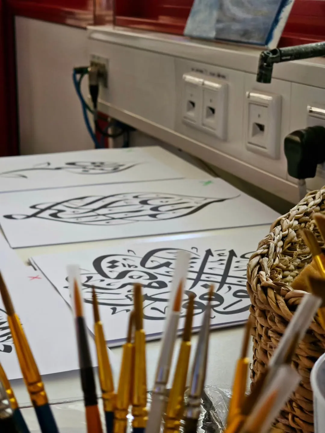 Pinsel und ein handgeschriebenes arabisches Kunstwerk bei einem MHU-Kalligraphie-Workshop.