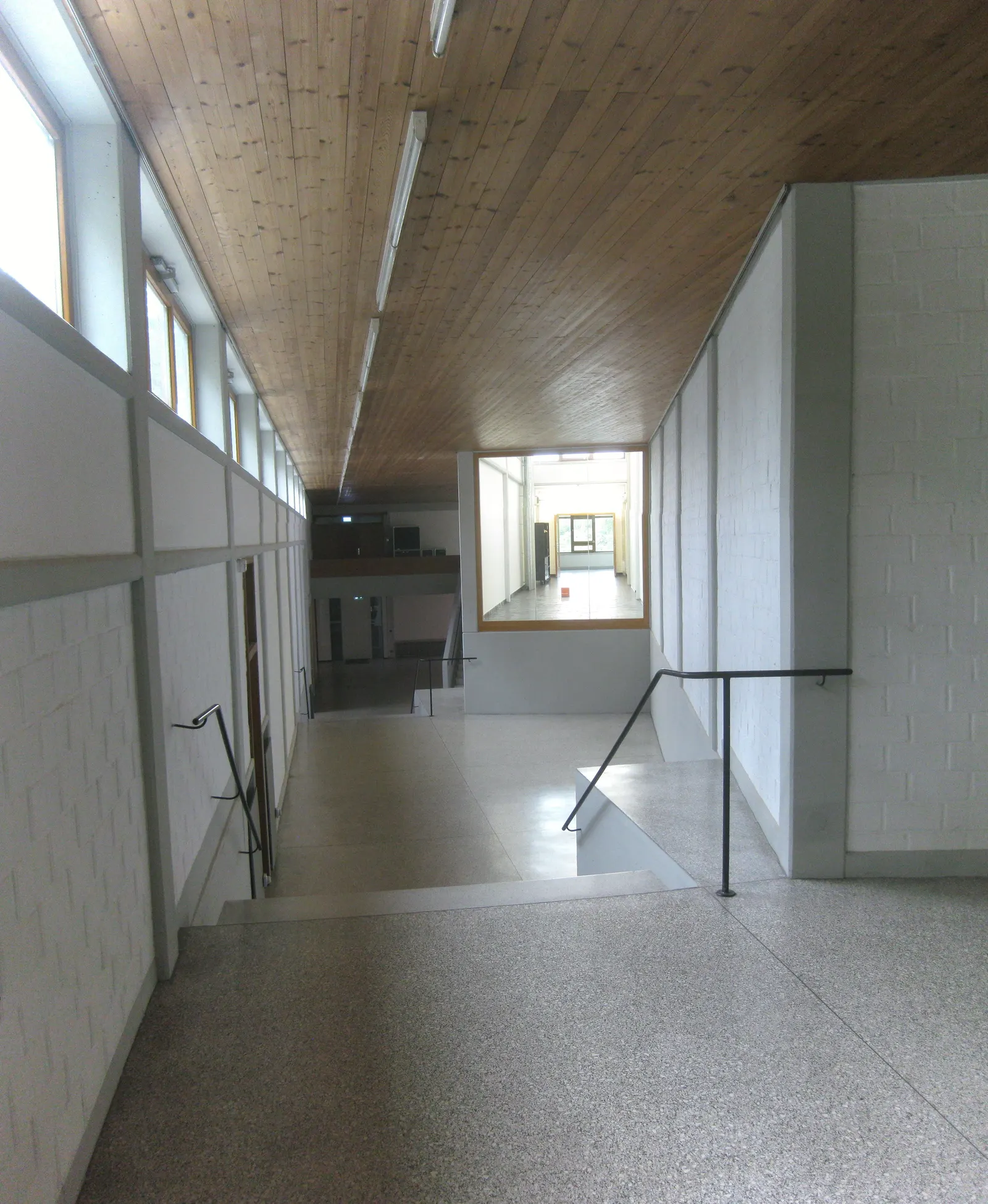 Ein schlichter Flur im HfG-Gebäude mit Holzdecke, weißen Wänden und einem Fensterband